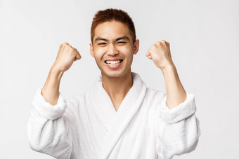 美水疗中心休闲概念满意亚洲男人。浴袍拳头泵很高兴微笑广泛的很高兴赢得奖实现目标庆祝胜利白色背景