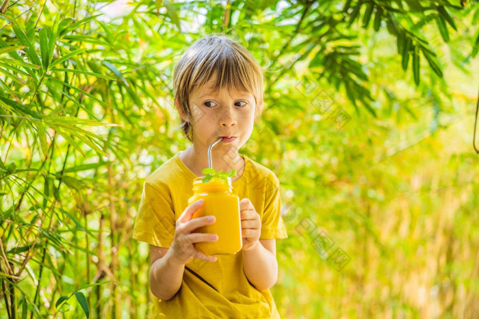 男孩喝多汁的奶昔芒果玻璃梅森Jar健康的生活概念复制空间