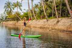 站桨董事会女人桨登机湖站快乐paddleboard蓝色的水行动拍摄年轻的女人桨董事会