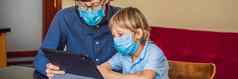 男孩研究在线首页平板电脑父亲帮助学习父亲儿子医疗面具保护coronovirus研究检疫全球流感大流行科维德病毒横幅长格式