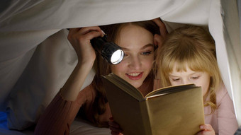 年轻的妈妈。阅读晚安故事童话孩子女儿<strong>羽绒被</strong>毯子晚上房间