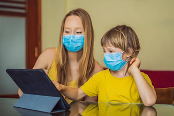 男孩研究在线首页平板电脑妈妈帮助学习妈妈儿子医疗面具保护coronovirus研究检疫全球流感大流行科维德病毒