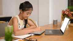 可爱的亚洲女孩坐着首页厨房学习虚拟距离在线类移动PC电脑教育学校概念