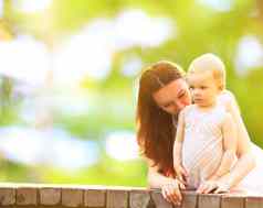 年轻的妈妈。婴儿户外温暖的夏天一天