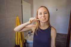 年轻的高加索人女人刷牙牙齿竹子牙刷