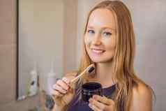 年轻的女人刷牙牙齿黑色的牙粘贴活跃的木炭黑色的牙刷浴室