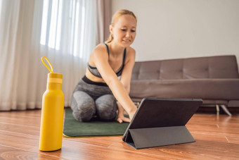 健身女人锻炼地板上首页看健身视频平板电脑人体育在线coronovirus
