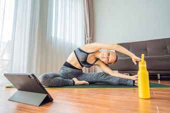 健身女人锻炼地板上首页看<strong>健身视频</strong>平板电脑人体育在线coronovirus