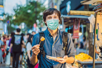 年轻的男人。旅游医疗面具吃典型的朝鲜文街食物走街首尔辣的快食物简单的发现当地的朝鲜文殉道灵魂韩国游客恐惧法律顾问病毒医疗戴面具的游客