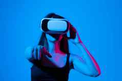 快乐的女孩手穿虚拟现实护目镜玩游戏霓虹灯光未来技术概念元宇宙