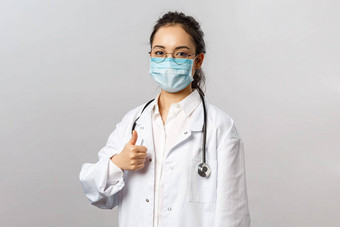科维德冠状病毒医疗保健医生概念年轻的确定亚洲女医生保证质量医院设备显示翘拇指穿白色外套听诊器医疗面具