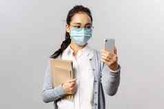 科维德病毒健康医学概念年轻的亚洲女孩医疗面具持有笔记本电脑工作报告采取自拍智能手机videocalling朋友社会距离