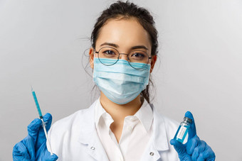 医生infectionist研究科维德概念特写镜头亚洲女护士医疗面具手套白色外套持有注射器安瓿冠状病毒疫苗治愈人