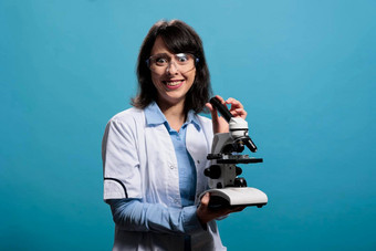 疯狂的科学家微笑令人毛骨悚然的现代显微镜仪器蓝色的背景