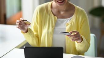 微笑年轻的女人持有信贷卡购物在线互联网银行服务电脑平板电脑