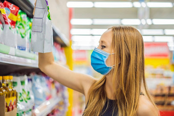 警觉女穿医疗面具冠状病毒杂货店购物超市商店健康安全流感大流行概念年轻的女人穿保护面具储备食物