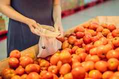 女人选择西红柿超市塑料袋可重用的袋购买蔬菜浪费概念