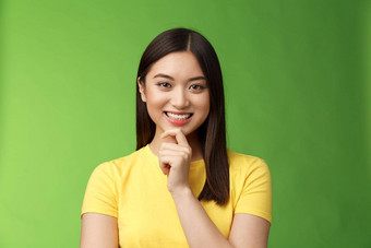 聪明的自信的有创意的亚洲女学生使有趣的研究<strong>假设</strong>微笑感兴趣触摸下巴深思熟虑的好计划的想法思考思考选择绿色背景