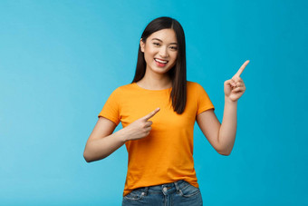 快乐的活泼的可爱的亚洲女人微笑笑乐观的指出上角落里给建议选择购物在线咧着嘴笑幸福的热情的促销蓝色的背景
