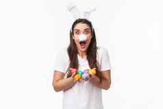 肖像兴奋快乐年轻的有趣的女人穿兔子服装耳朵毛茸茸的鼻子面具持有彩色的鸡蛋庆祝假期复活节聚会，派对站惊讶白色背景
