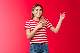 友好的快乐的好看的年轻的金发碧眼的朝鲜文女孩指出上左角落里建议完美的的地方推荐产品微笑广泛的给建议介绍好复制空间站红色的背景
