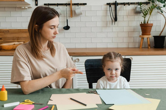 可爱的愤怒的学前教育女孩有创意的家庭作业妈妈坐着表格生活房间争论问题使工艺品幼儿园
