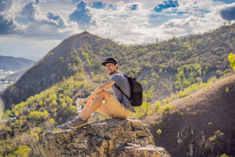 年轻的男人。当地的旅游坐在岩石享受视图城市当地的旅游概念旅游科维德