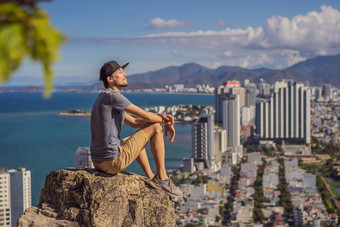 年轻的男人。当地的旅游坐在岩石享受视图城市当地的旅游概念旅游科维德