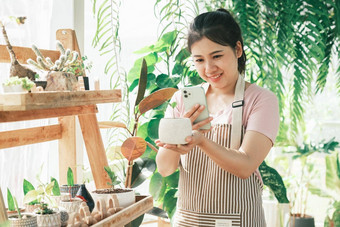 微笑年轻的女人采取智能手机图片植物小商店