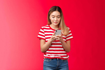 受欢迎的亚洲女生活方式博主发布照片在线持有智能手机电话显示滚动饲料女人微笑很高兴放松小工具站红色的背景