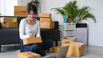 年轻的女人在线卖方写作地址纸板盒子准备包裹盒子产品航运