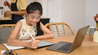可爱的亚洲女孩坐着首页厨房<strong>看学习</strong>在线虚拟教室电脑移动PC电子<strong>学习</strong>教育概念