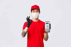 非接触式交付安全购买购物冠状病毒概念友好的亚洲快递红色的统一的帽t恤穿医疗面具手套显示回来终端标志