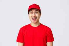 交付非接触式订单购物概念兴奋交付的家伙红色的统一的帽t恤快递微笑逗乐相机热情的做广告航空公司服务灰色背景