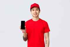 交付应用程序在线购物航运概念微笑交付的家伙红色的统一的帽t恤显示移动电话屏幕建议下载应用程序奖金订单