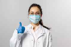 科维德冠状病毒医疗保健医生概念肖像乐观亚洲女医生保证翘拇指穿医疗面具防止捕捉病毒白色外套
