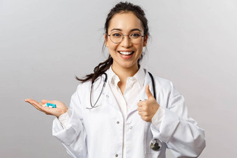 医疗保健医学药店概念肖像乐观的美丽的亚洲医生白色外套显示翘拇指持有药片建议规定药物治愈疾病保持健康的