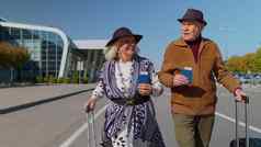 高级养老金领取者游客祖母祖父保持机场大厅行李轮子