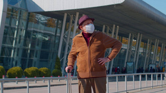 高级养老金领取者旅游祖父穿保护脸面具避免冠状病毒机场