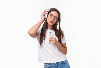 技术生活方式音乐概念肖像乐观的热情的年轻的女孩眼镜听歌曲耳机唱歌太棒了跟踪持有移动电话跳舞