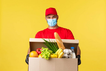 外卖交付科维德检疫食品杂货概念快乐的微笑快递红色的统一的医疗面具将食物盒子订单客户端积极的表达式黄色的背景