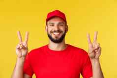 特写镜头快乐的友好的快递交付的家伙红色的t恤帽显示和平迹象微笑住乐观科维德流感大流行站黄色的背景