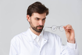 医院医疗保健工人科维德治疗概念特写镜头英俊的有胡子的医生实习医生风云密切眼镜镜片挑选镜片眼镜灰色背景