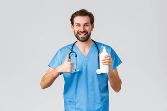 医疗保健工人流感大流行冠状病毒爆发概念英俊的医生推荐洗手个人卫生显示翘拇指手洗手液穿实习医生风云灰色背景