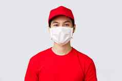 特写镜头肖像快乐的亚洲交付的家伙医疗面具红色的帽统一的t恤微笑眼睛客户采取订单安全措施防止科维德传播