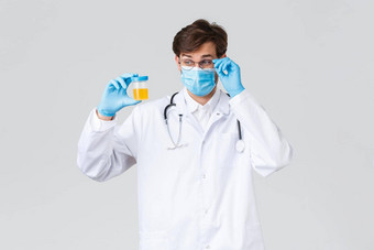 医院医疗保健工人科维德治疗概念实验室技术员医生检查尿液样本实验室穿保护医疗面具手套感兴趣灰色背景