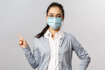 科维德病毒健康医学概念肖像年轻的严肃的表情亚洲女孩医疗面具防止传播冠状病毒流感指出左显示信息疾病