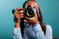 工作室拍摄年轻的成人女人数码单反相机相机拍摄照片站蓝色的背景