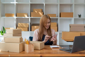 年轻的女人小业务老板在线购物首页确认订单客户移动手机准备包产品背景锻造企业家自由生活风格概念