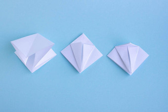 手工制作的白色时尚的几何多边形纸折纸鱼蓝色的背景一步
